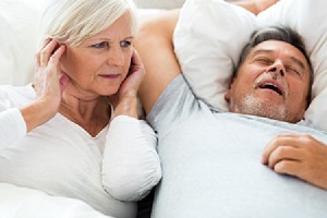 Frustrated woman next to snoring man in need of sleep apnea therapy
