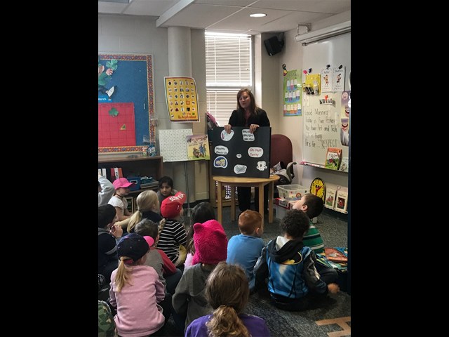 Dental team member giving dentistry presentation to children in a classroom
