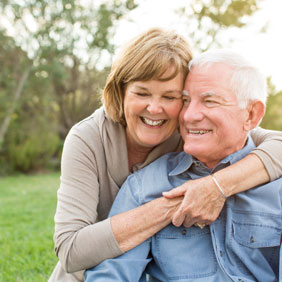 Older couple with dentures smiling together outdoors