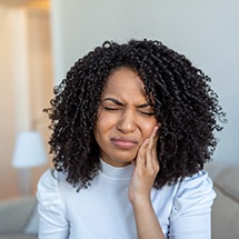 a woman holding her cheek due to failed dental implant