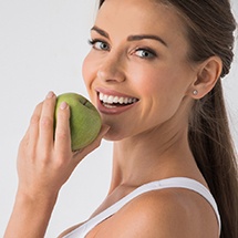 woman biting into a green apple 
