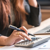 Woman looking at computer and using calculator