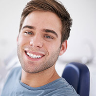 Man in dental chair smiling after fluoride treatment
