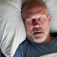 Man in black shirt sleeping soundly thanks to sleep apnea therapy
