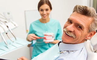 Older man smiling after receiving dental services