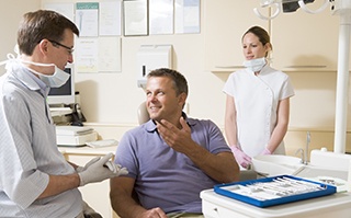 Man talking to dentist about tooth replacement with dental implants