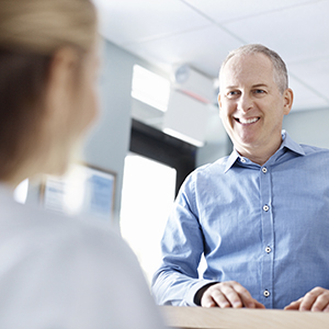 Man talking to team member at the dental office reception desk