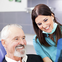 Dental team member showing patient his smile after all ceramic dental restoration