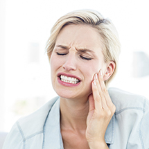 Lady grimacing in pain and holding cheek