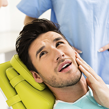 Pained man holding cheek before T M J therapy