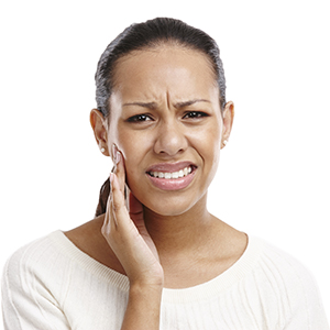 Woman in need of emergency dentistry holding cheek in pain