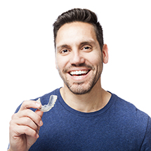 Man holding Invisalign clear aligner smiling