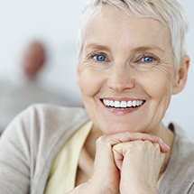 Senior woman sharing healthy smile after dental crown supported fixed bridge restoration