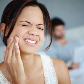 Lady in pain holding cheek before wisdom tooth extraction